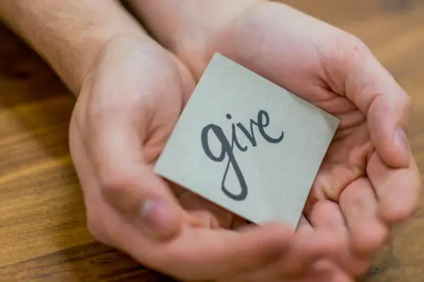 giving-back-concept-charlotte-treatment-center Hands holding a note with the word 'give', symbolizing the spirit of giving back at a Charlotte treatment center.