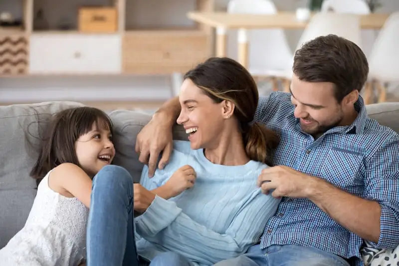 happy-family-dilworth-center-addiction-recovery-charlotte Happy family sitting on a couch, representing the support offered by Dilworth Center's addiction recovery programs in Charlotte, NC.