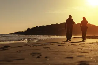 sober-living-couple-walking-on-beach-at-sunset Couple enjoying a sober living lifestyle walking on the beach at sunset, highlighting a serene and healthy environment.