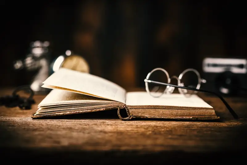 first-recorded-problems-benzo-addiction-withdrawal-recovery-history An open vintage book with reading glasses placed beside it on a wooden table, symbolizing the historical context and first recorded issues related to benzo addiction and withdrawal.