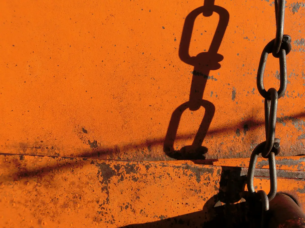 Shadow of a chain on an orange surface, depicting the feeling of kratom withdrawal symptoms.